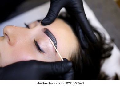 a close-up of the procedure of coloring the eyebrows with paint is performed after the procedure of lamination of the eyebrows