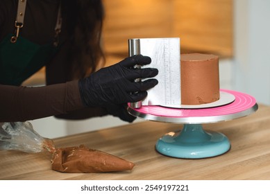 Close-up. The process of a confectioner leveling the surface of a chocolate cake with a bench scraper.