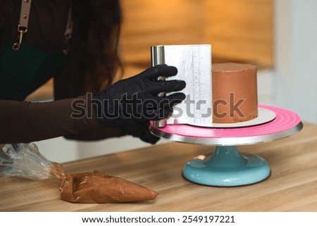 Close-up. The process of a confectioner leveling the surface of a chocolate cake with a bench scraper.