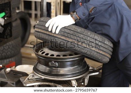 Close-up of the process on a tire-changing machine: a mechanic dismounts a car wheel (removing a tire from or mounting one onto a stamped steel rim).