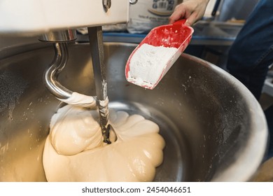 Close-up of the process of pouring flour and kneading pizza dough in a kneading machine in a bakery. High quality photo - Powered by Shutterstock