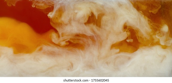 Closeup Process Of Pouring Milk, Cream Into Transparent Glass Cup Of Traditional English Black Tea. Abstract Brown Background With Light Stains. Mixing Of Liquids. Hot Drinks, Beverages Concept.