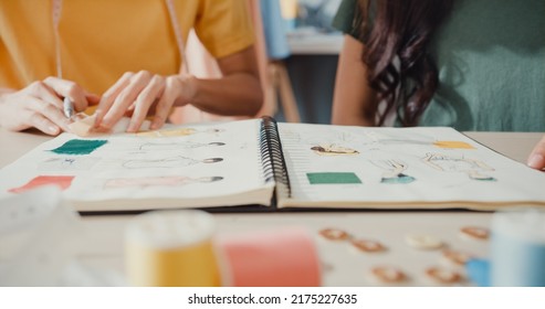 Close-up profession Asia lady designer teamwork meeting sketch book work on new collection share idea in shop. Young tailor discuss color for new cloth in workshop at table, Concept of collaboration. - Powered by Shutterstock