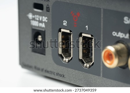 Close-up of professional audio interface rear panel featuring digital S-PDIF RCA connectors and FireWire ports for high-speed studio recording and music production connectivity on grey metal housing.