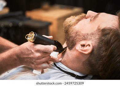 Close-up of professional barber trimming client's beard. Male hairdresser serving client with thin beard by clipper. Isolated photo of man getting his haircut done. - Powered by Shutterstock