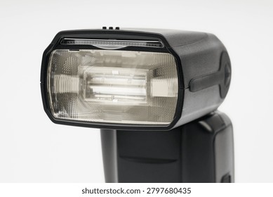 Close-up of a professional camera flash unit showing the fresnel lens and reflector isolated on a white background
