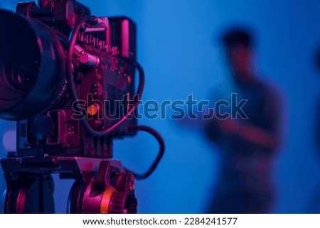 Close-up of professional camera setting for shooting with operator working in background