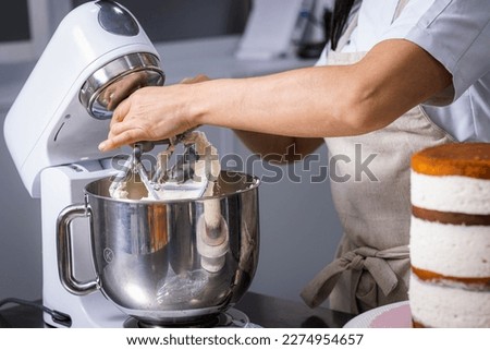 Close-up of a professional chef's hands working the batter with a food processor.