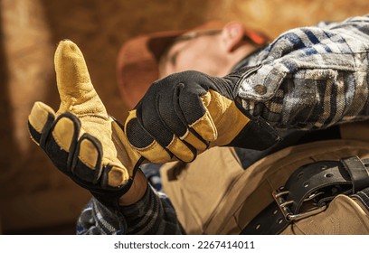 Closeup of Professional Construction Worker Putting On Industrial Gloves Before Starting Work at Building Site.