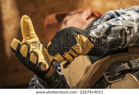 Closeup of Professional Construction Worker Putting On Industrial Gloves Before Starting Work at Building Site.