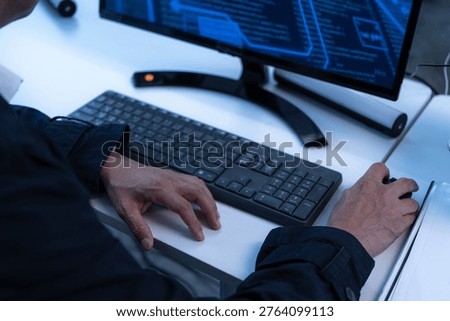 Close-up of a professional developer using a computer mouse and keyboard to analyze complex digital data on a screen. Concept of cybersecurity, coding, and high tech software engineering workspace