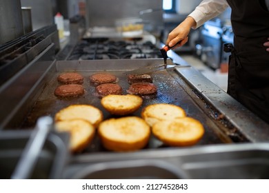 Close-up of professional female chef preparing burgers indoors in restaurant kitchen. - Powered by Shutterstock