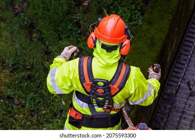 Close-up Of A Professional Gardener Mowing The Lawn In Full Equipment