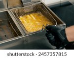 close-up in professional kitchen frying French fries in oil in a deep fryer