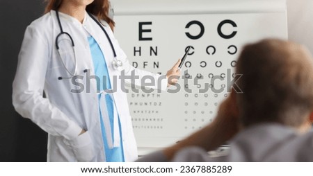 Close-up of professional ophthalmologist checking vision of patient. Experienced oculist pointing to letter in vision test table. Healthcare and prevention concept