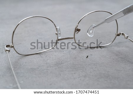 Closeup of professional repairing of eyeglasses with ophthalmology instrument in clinic office and optics. Installation of nose pads in glasses. Fixing of broken glasses