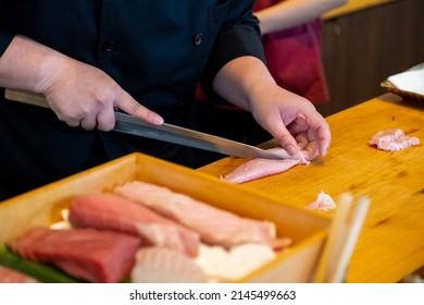 Close-up Professional sushi chef hand using knife cutting Otoro ( Tuna belly part ) sashimi prepare to make perfect sushi with precision and confidence.