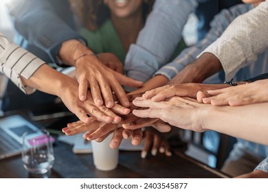 Close-up of a professional team's hands piled together, exemplifying unity and teamwork in a corporate environment. - Powered by Shutterstock