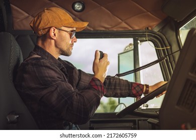 Closeup Of Professional Truck Driver Communicating Through His CB Radio While Completing A Cargo Delivery. Useful Trucker Tools.