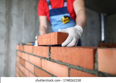 Close-up Of Professional Worker Putting One Red Brick On Another. Process In Progress. Male In Protective White Gloves. Construction Site And Renovation Concept