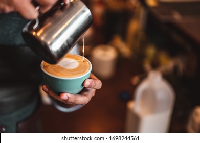 Close-up of professionally extracting coffee by barista with a pouring steamed milk into coffee cup making beautiful latte art. coffee, extraction, deep, cup, art, barista concept. 