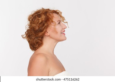 Closeup Profile Of Happy Mature Woman Smiling And Looking Upwards. Beautiful Red Haired Lady Posing Isolated On White Background In Studio.