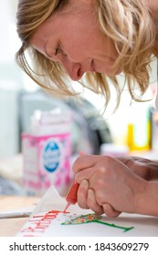 Close-up Profile Shot Of A Joyous Woman Decorating A Birthday Cake By Writing Over It With Edible Icing.