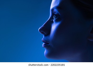 Closeup profile view young pretty girl and well  kept skin isolated over dark blue background in neon light  Concept high fashion  emotions  style  inspiration  Art portrait