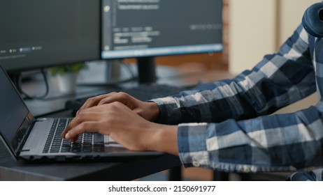 Closeup of programer hands typing machine learning code on laptop keyboard in front of computer screens with programming interface. System engineer writing algorithm for online cloud computing.