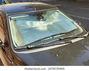 Closeup of protective reflective surface under the windshield of the passenger car parked on a hot day, heated by the sun's rays inside car. Sunshade, Heat protection, auto accessory concept