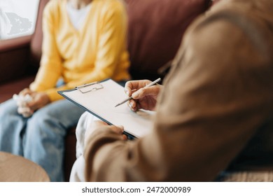 Close-up of a psychologist's hands writing down notes about a patient in a notebook. The psychologist makes a social survey of the reference group. A professional is talking to a client.