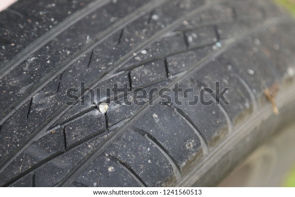 Closeup of punctured tire of car caused by a\
screw. Normal car\
accident.