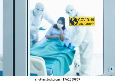 Close-up Of Quarantine COVID-19 Sign At Hospital Door. Blur Medical Doctor Team Wearing Protective Clothing. Healthcare Woman Wearing Mask Is Patient Coronavirus COVID Outbreak Control Pandemic Virus