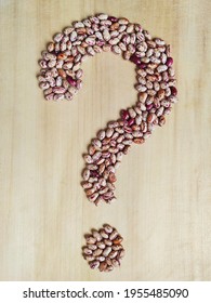 Close-up of question  mark collected from white-red haricot beans on a wooden background.