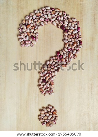 Close-up of question  mark collected from white-red haricot beans on a wooden background.