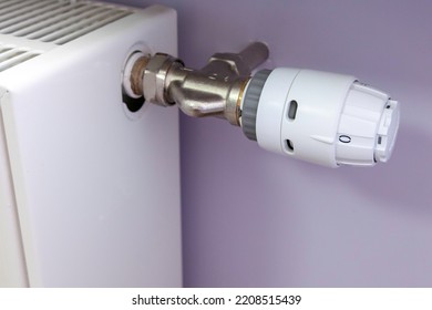 Close-up Of Radiator Thermostatic Brass Valve At Zero Value On The Light Pastel Color Painted Wall. Central Heating Installation, Smart Home.