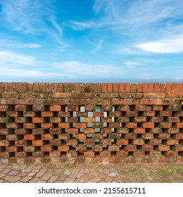 Close-up of a railing of a bridge (parapet) made of old bricks against a blurred blue sky with clouds. Veneto, Italy, Europe.
