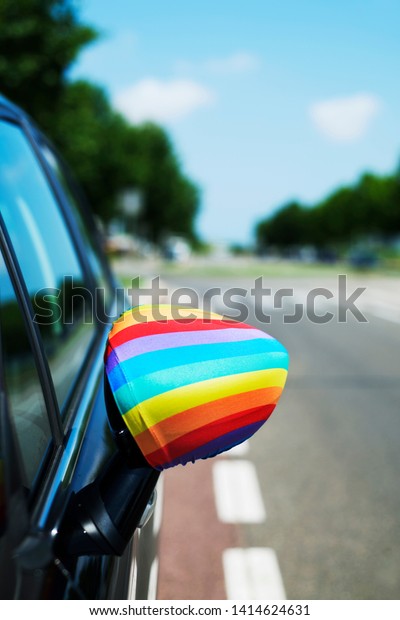 closeup of a rainbow flag in the wing mirror of a\
car on the street