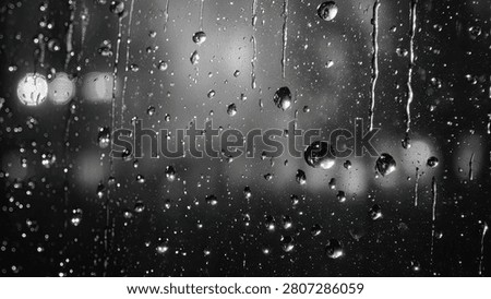 Close-up of raindrops on a window pane at night, with blurred bokeh lights of a city in the background.