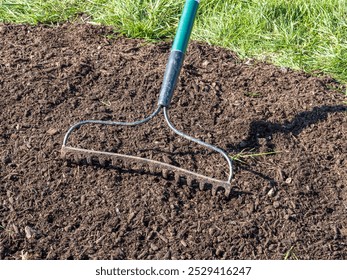 Close-up of a rake working on overseeding grass on a lawn.