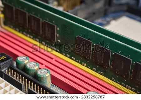Close-up of a RAM memory module installed on a motherboard, showing integrated chips, colored DIMM slots, and nearby capacitors. The image highlights the internal architecture of the hardware and the importance of the components that allow the efficient operation of a computing system.                     