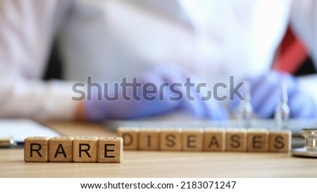 Close-up of rare disease words collected with wooden cubes. Female doctor on background. Healthcare, medicine and unusual disorders concept