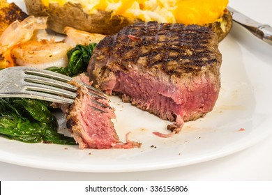 Closeup Of Rare Filet Mignon With Several Bites Taken.  Served With Shrimp And Twice Baked Potato On Wilted Spinach.