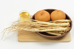 Close-up Of Raw Balloon Flower Roots And Two Pears On A Jar With A Glss Of Honey On Wood Cutting Board, South Korea
