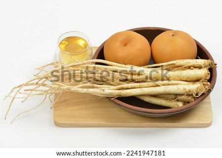 Close-up of raw balloon flower roots and two pears on a jar with a glss of honey on wood cutting board, South Korea
