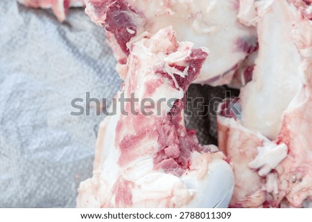 Close-up of raw beef bones with attached meat and fat, prepared for cooking, roasting, or making nutrient-rich bone broth in a kitchen setting.