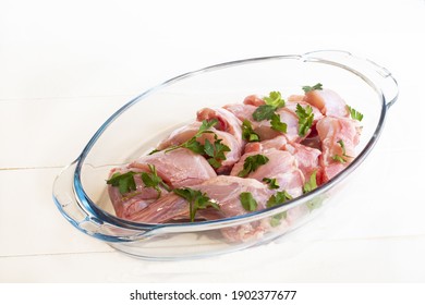 A closeup of the raw chopped chicken meat with cilantro leaf in a glass container