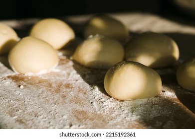 Close-up of raw dough balls and flour on wooden counter. Ready for baking. Sunlight. - Powered by Shutterstock