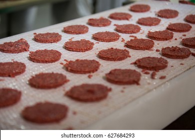 Close-up of raw meat patties on assembly line at meat factory - Powered by Shutterstock