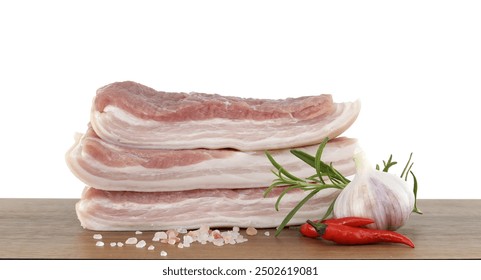 Close-up of raw pork belly slices with garlic, red chili peppers, and rosemary on a wooden cutting board. - Powered by Shutterstock